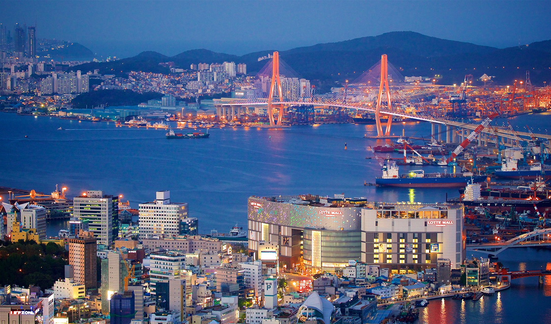 Mar de Busan onde passa uma ponte e tem muitos prédios bem iluminados ao redor